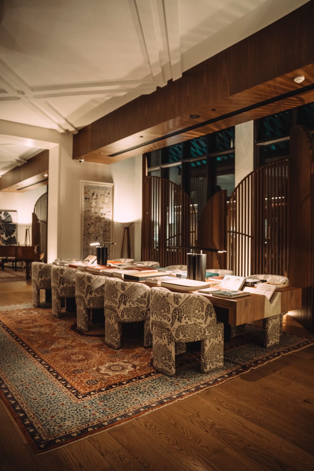 A warmly lit hotel lounge with timber screens and low armchairs