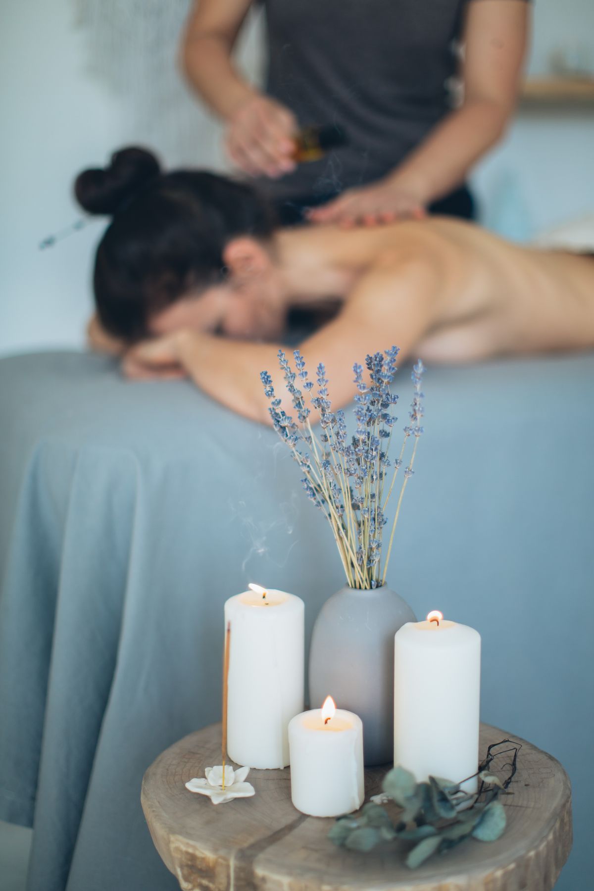 A guest relaxing during a massage, with lavender and lit candles in the foreground