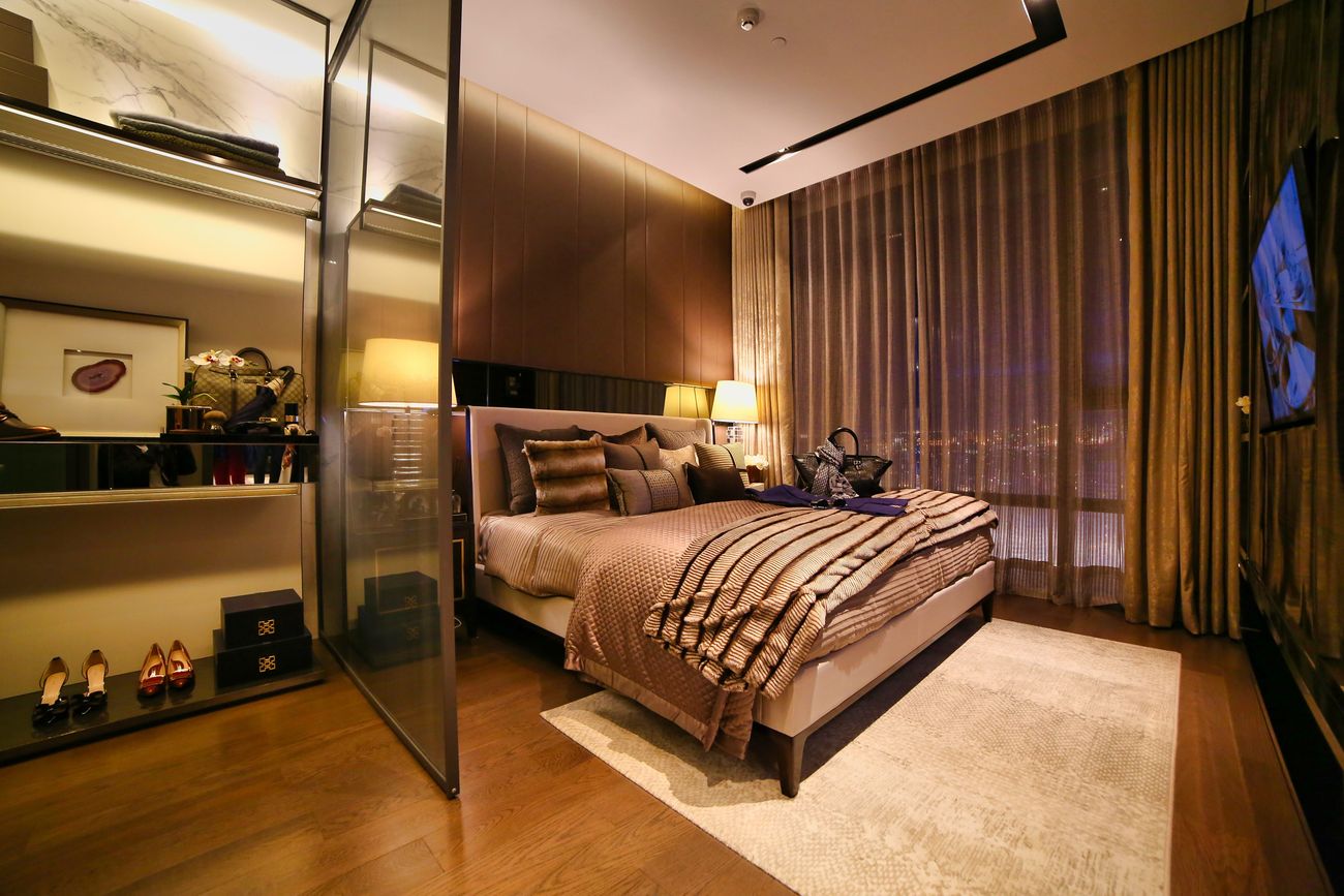 A sleek, low-lit hotel bedroom with dark timber and soft fabrics