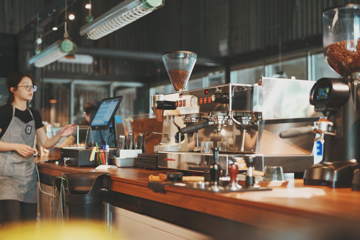 A barista at an espresso machine in a café