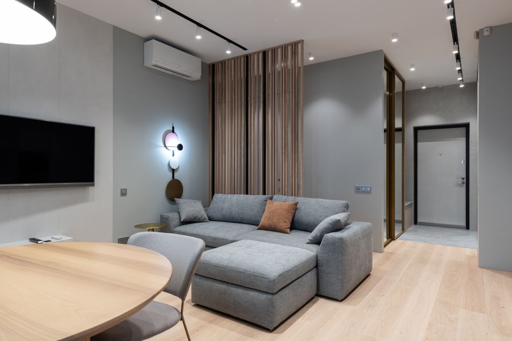 A modern apartment living room with a grey sofa and timber floors