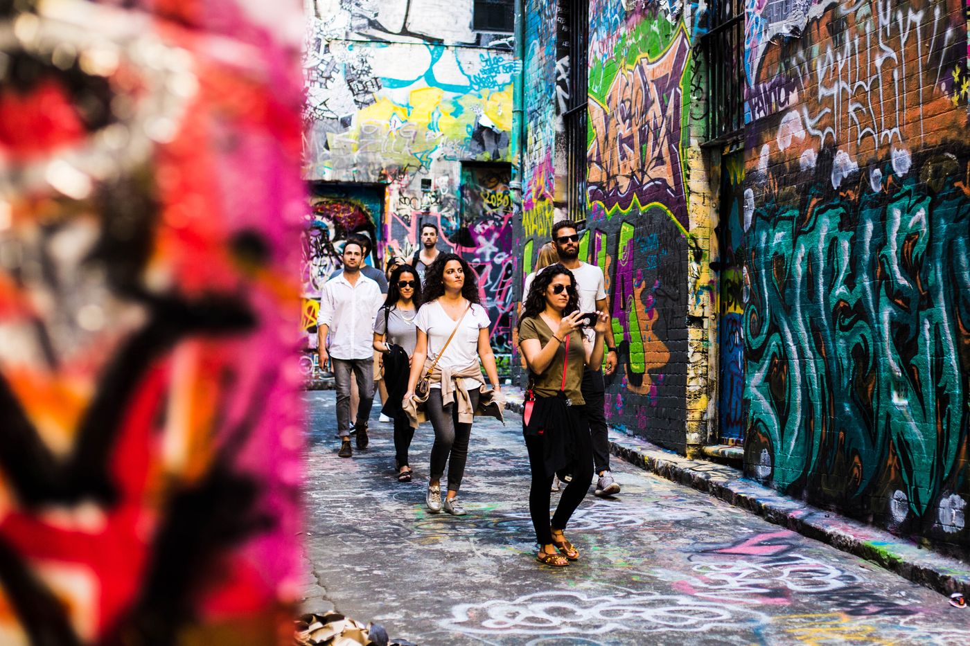 Visitors walking through a Melbourne laneway covered in colourful street art