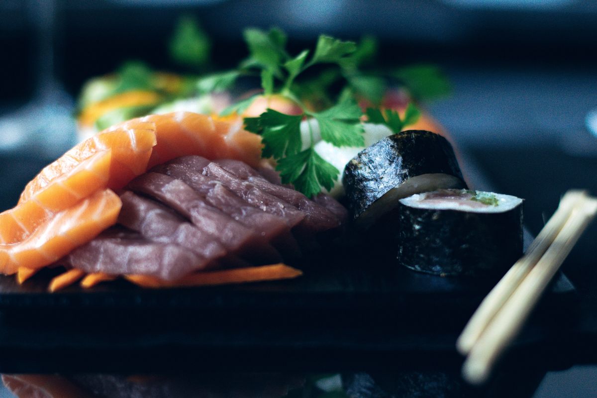 Sashimi and sushi rolls on a dark plate